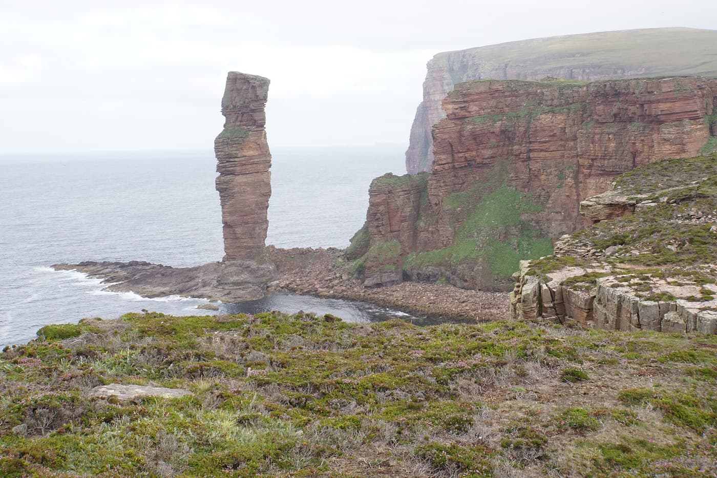 The Old Man of Hoy sea stack beside red sandstone cliffs