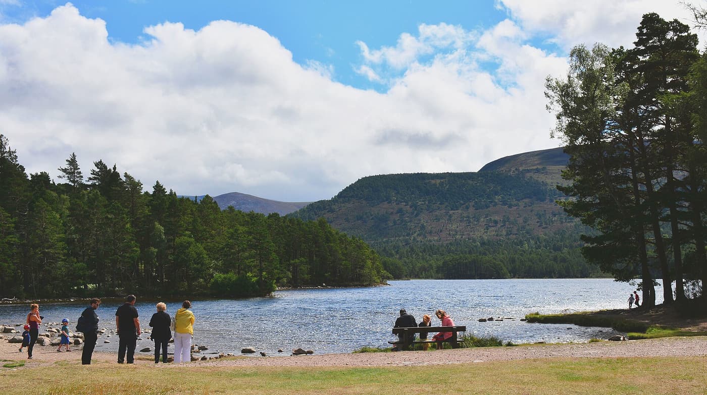 People on the shore of Loch an Eilein among the pines of Rothiemurchus