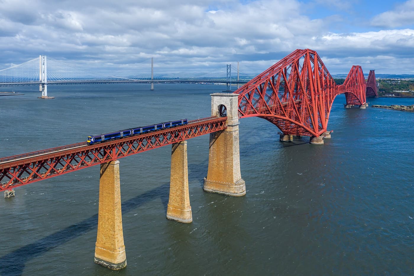 A ScotRail train crossing the red steel Forth Bridge